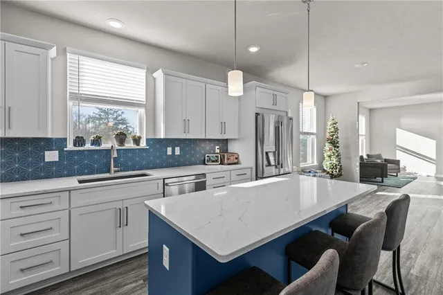 a large kitchen with cabinets chairs and refrigerator