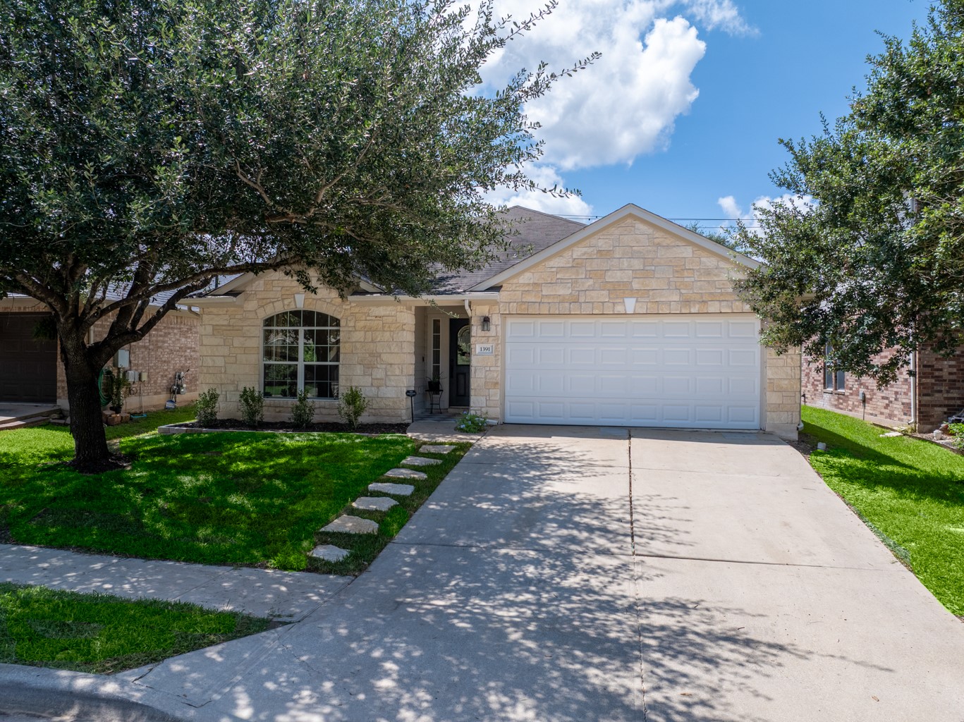 1391 Stone Rim Loop Buda, TX 78610 - Photo 29 of 35 Limestone facade and arched entry distinguish this charming residence, framed by mature trees and a neatly manicured lawn.
