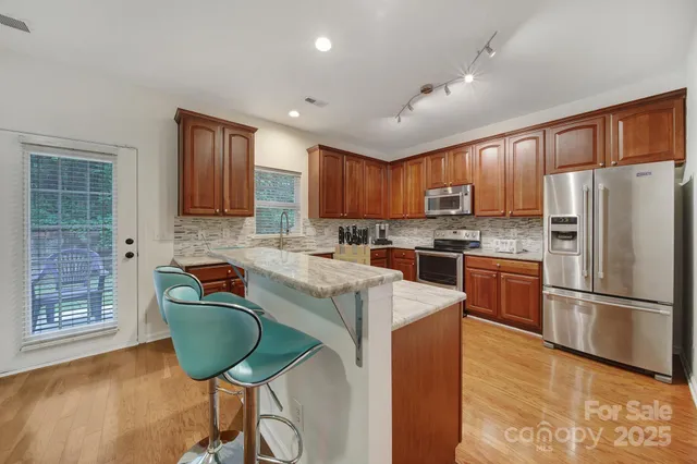 a kitchen with kitchen island granite countertop wooden cabinets a refrigerator a stove a sink and a oven