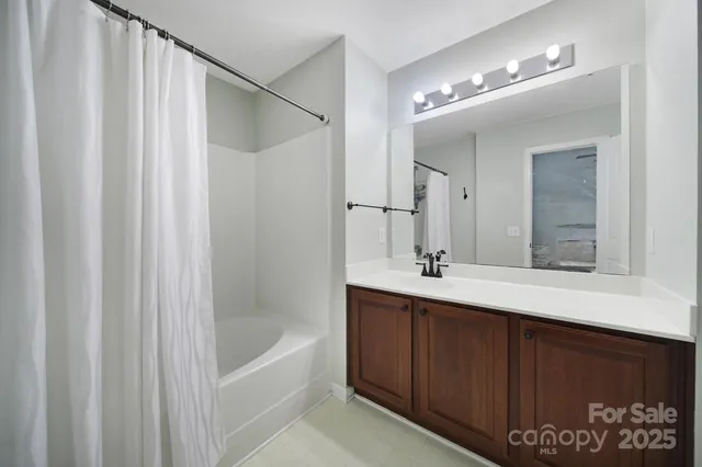a bathroom with a double vanity sink a large mirror and bathtub