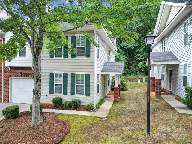 a view of a house with a yard and large tree