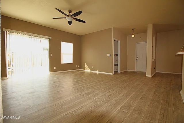 a view of an empty room with window and wooden floor