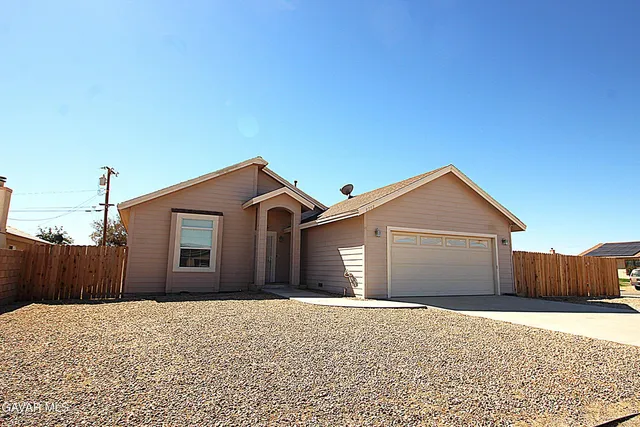 a front view of a house with a yard and wooden fence