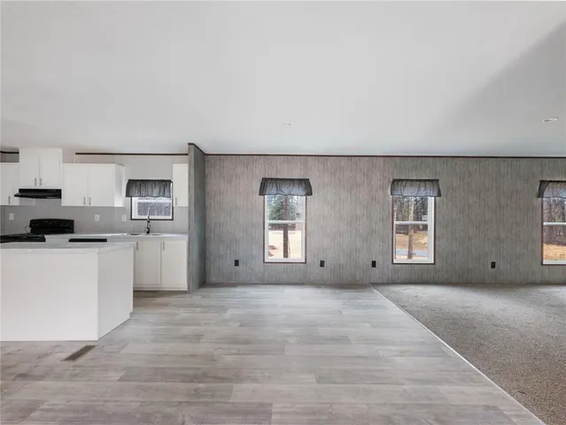a view of kitchen with stainless steel appliances granite countertop a stove a sink and white cabinets
