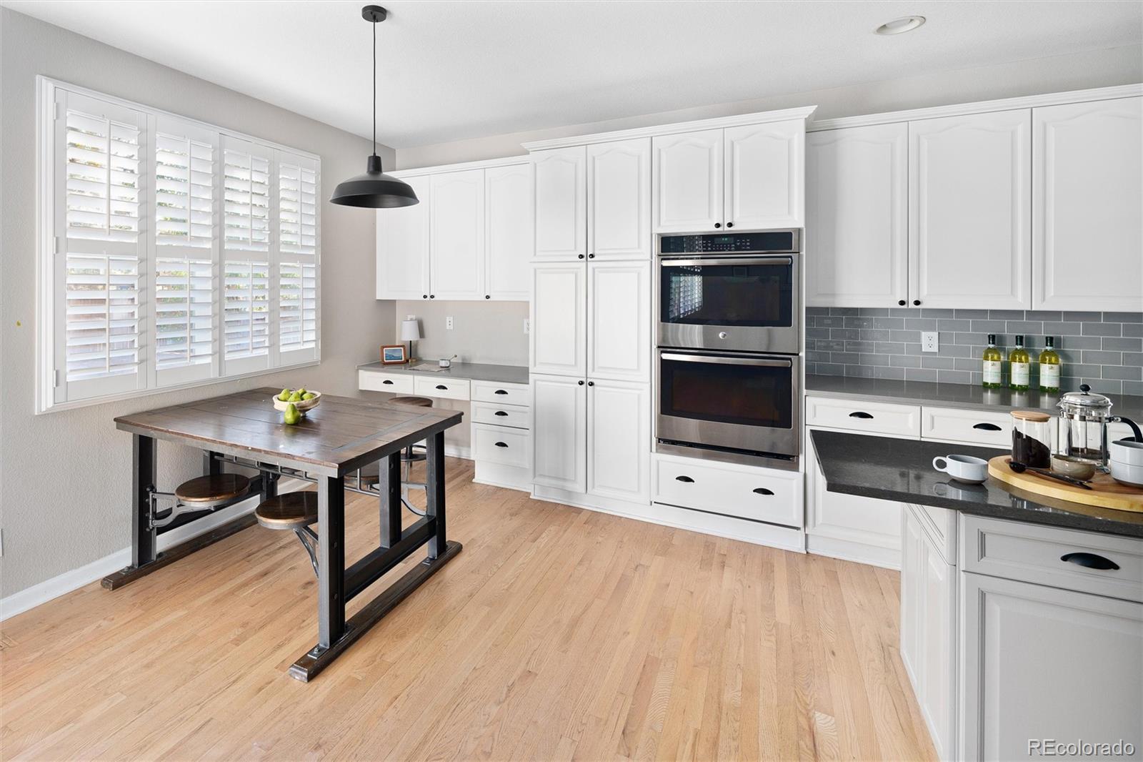2836 Rockbridge Circle Highlands Ranch, CO 80129 - Photo 22 of 50 a kitchen with stainless steel appliances a stove a sink dishwasher a microwave oven and a dining table with wooden floor