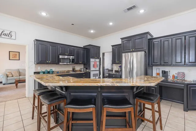 a large kitchen with stainless steel appliances granite countertop a sink a stove and a wooden cabinets