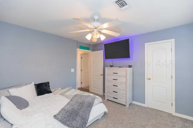 a bedroom with a bed a dresser and a chandelier