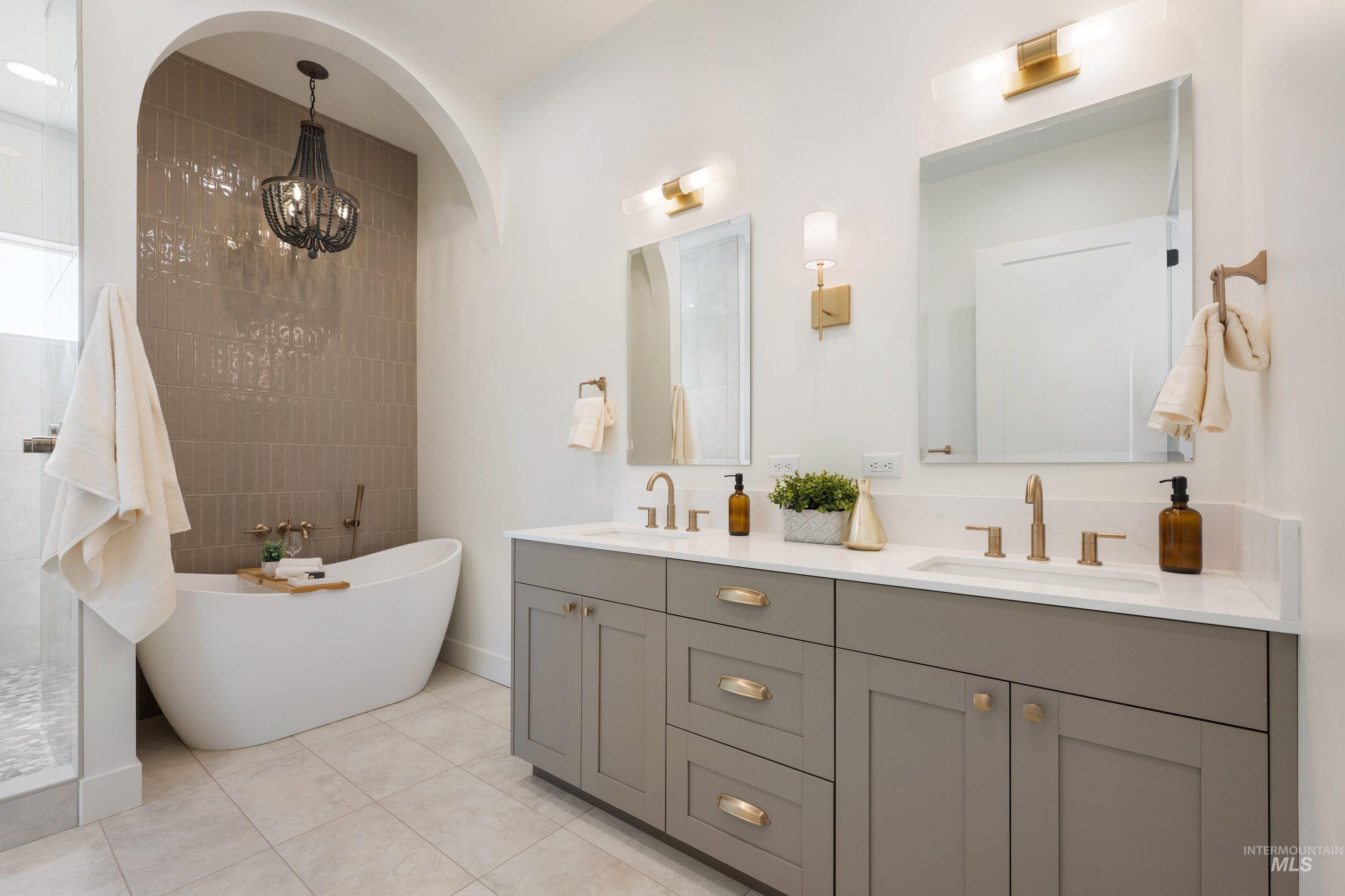 24763 Ardmore Court Caldwell, ID 83607 - Photo 32 of 50 Freestanding tub with wall-mounted brass fixtures, complemented by a textured tile accent wall and a dark chandelier