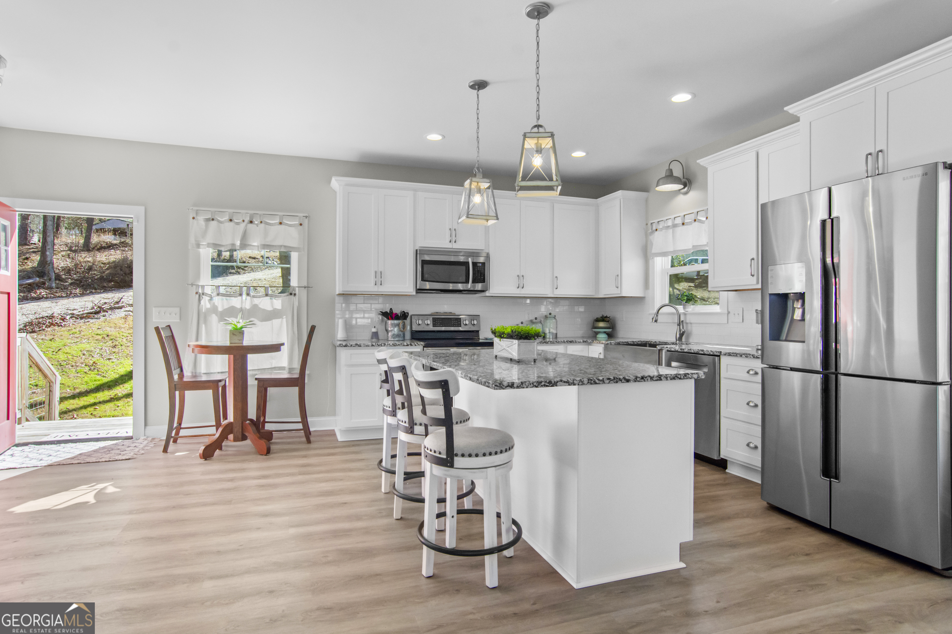 188 Sunhaven Lane Sparta, GA 31087 - Photo 17 of 63 a kitchen with stainless steel appliances granite countertop a refrigerator a microwave oven a stove a dining table and chairs with wooden floor