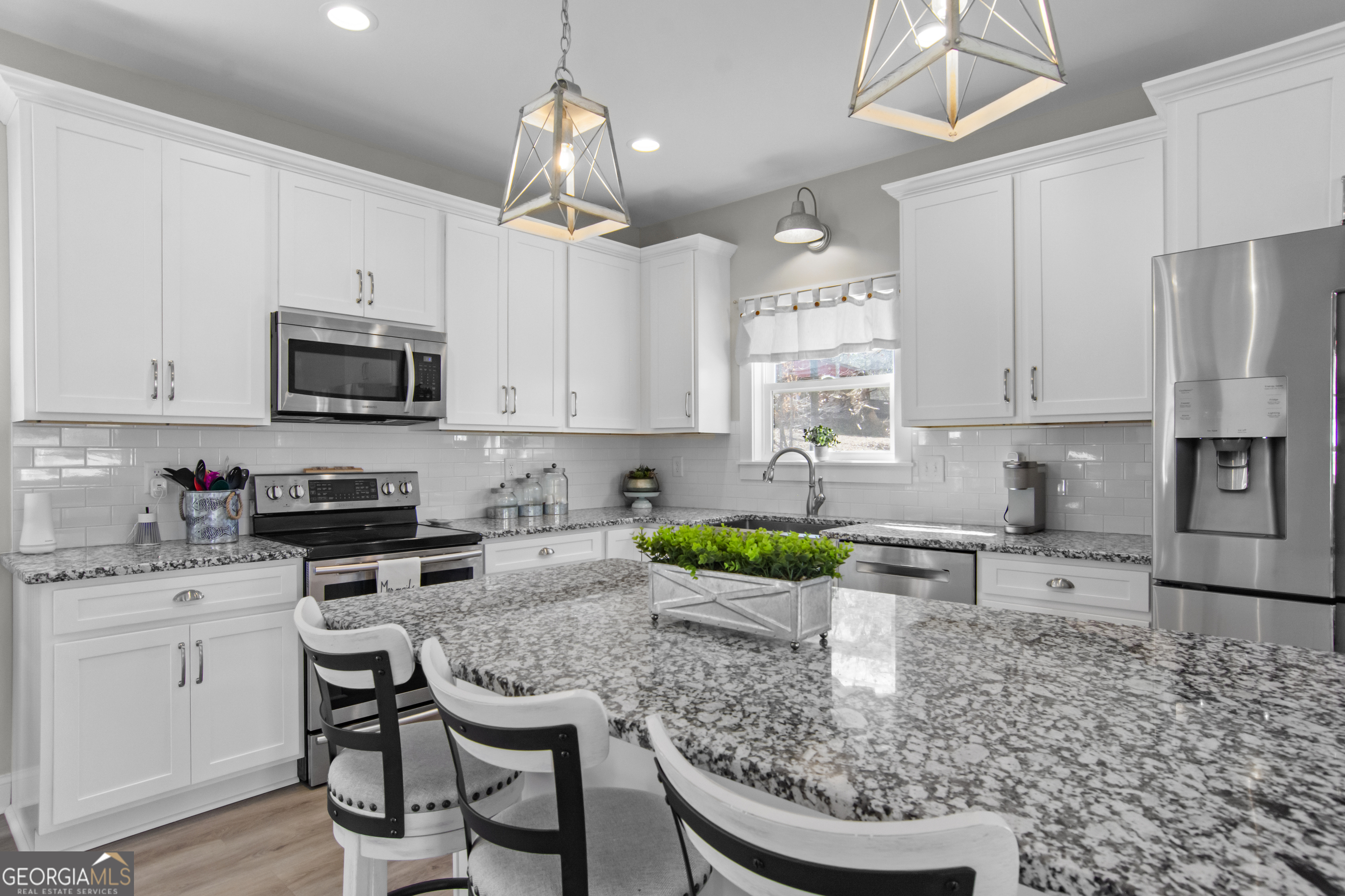 188 Sunhaven Lane Sparta, GA 31087 - Photo 22 of 63 a kitchen with stainless steel appliances granite countertop a stove a sink a microwave a dining table and chairs with white cabinets