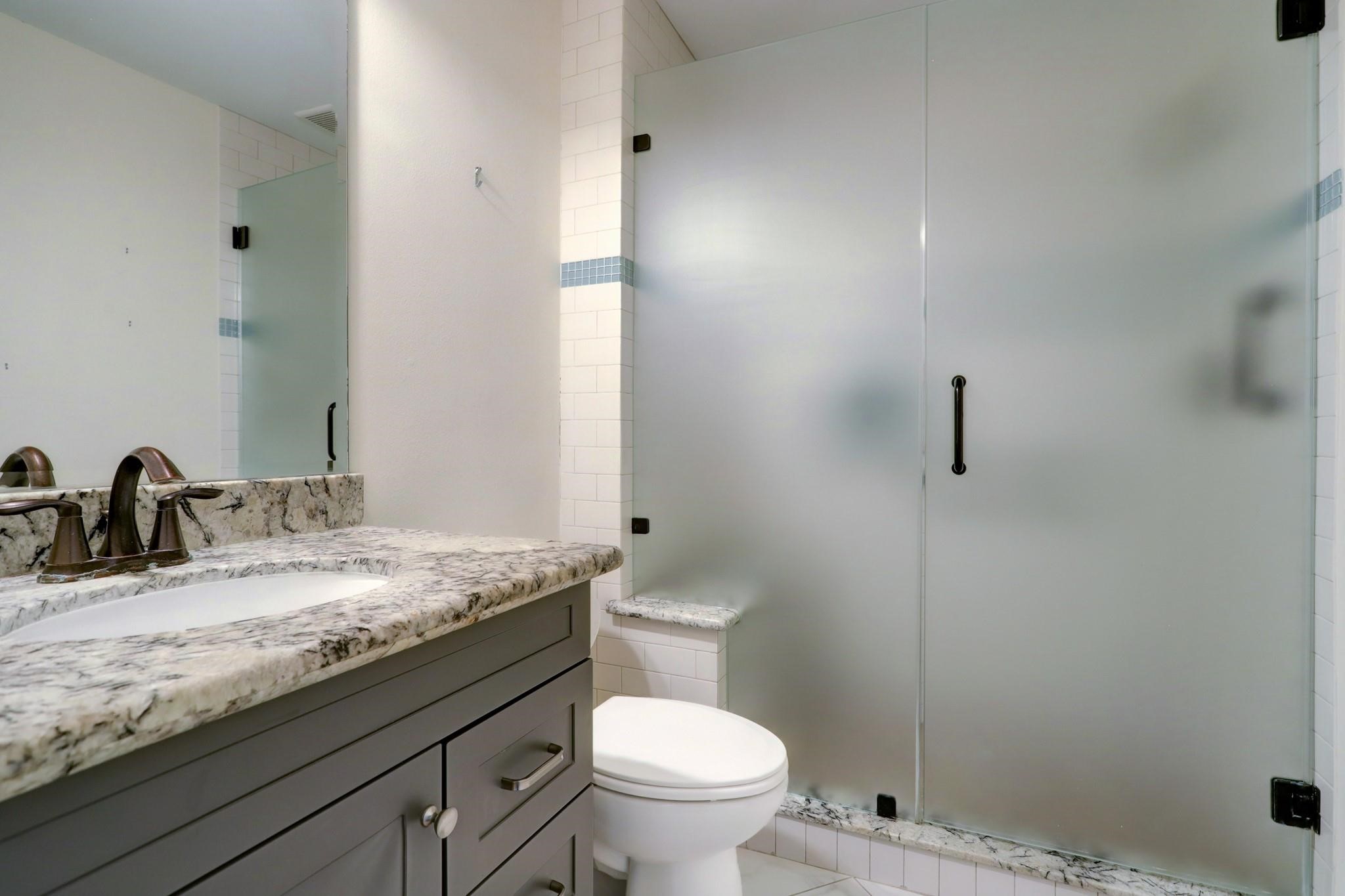 9410 Pipestone Street Houston, TX 77074 - Photo 3 of 10 a bathroom with a granite countertop toilet a sink and a mirror