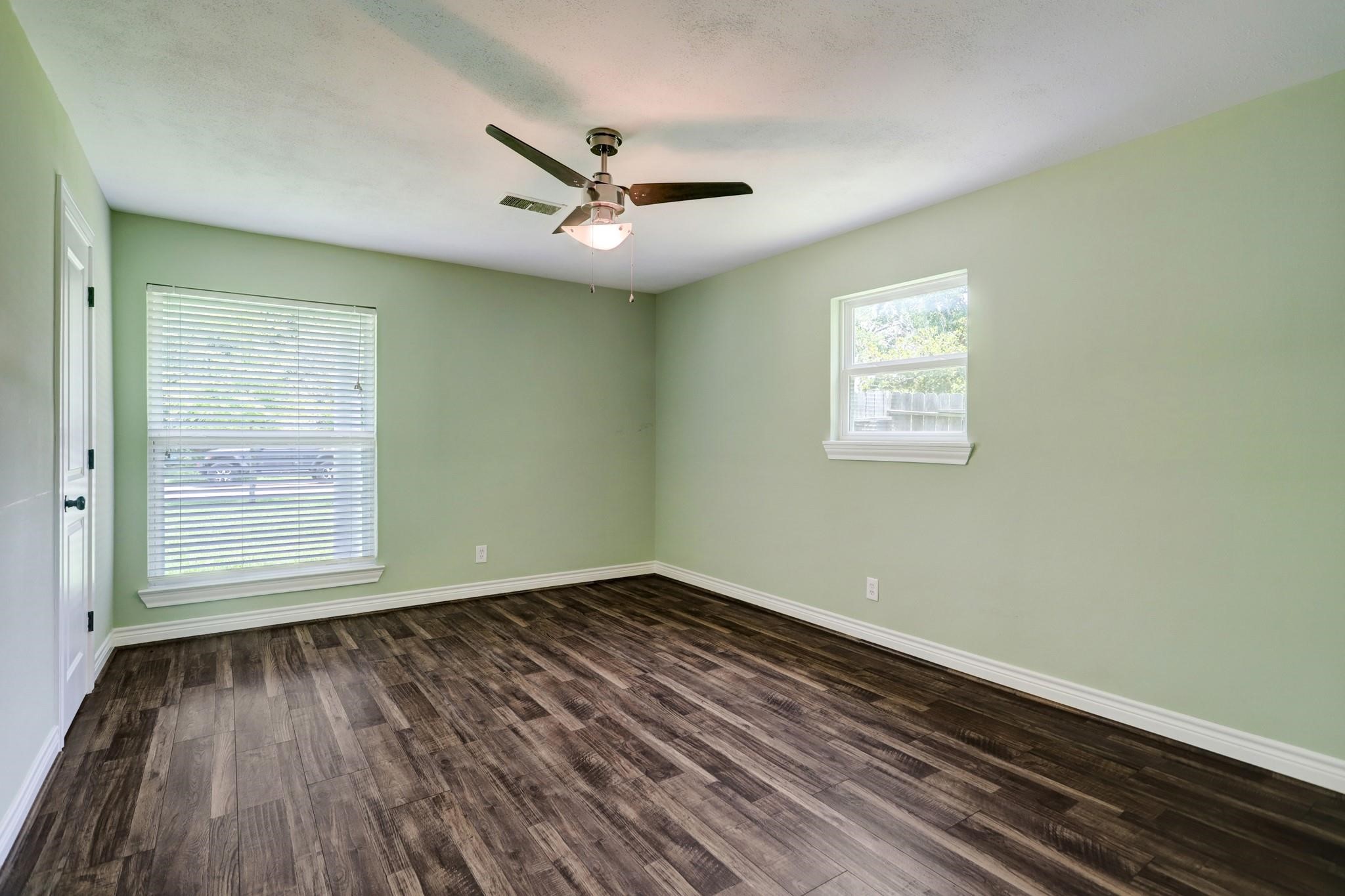9410 Pipestone Street Houston, TX 77074 - Photo 5 of 10 an empty room with wooden floor ceiling fan and windows