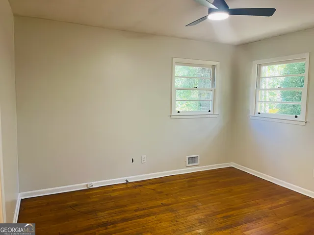 a view of an empty room with wooden floor and a window