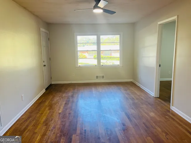 an empty room with wooden floor and windows
