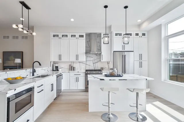 a kitchen with stainless steel appliances kitchen island granite countertop a sink a stove a dining table and chairs