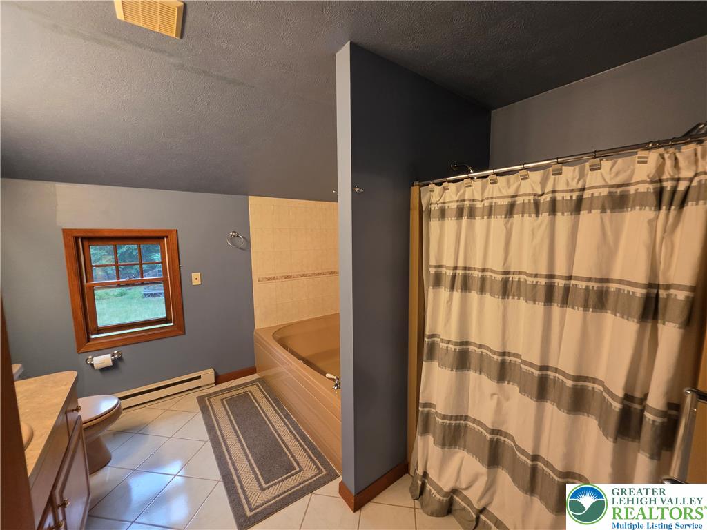 211 Murphy Circle Bushkill, PA 18324 - Photo 11 of 28 A well-lit bathroom features a built-in tub and a shower with a privacy curtain.