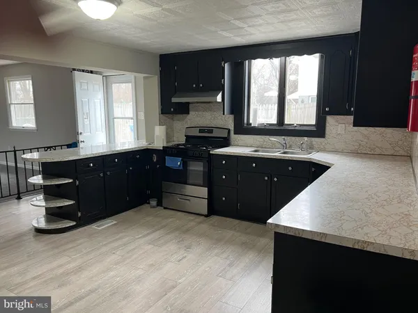 a large kitchen with granite countertop a sink window and cabinets
