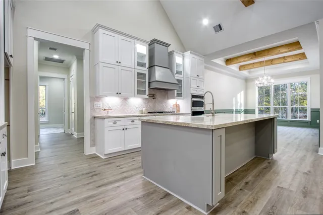 a large kitchen with stainless steel appliances granite countertop a lot of counter space and wooden floors