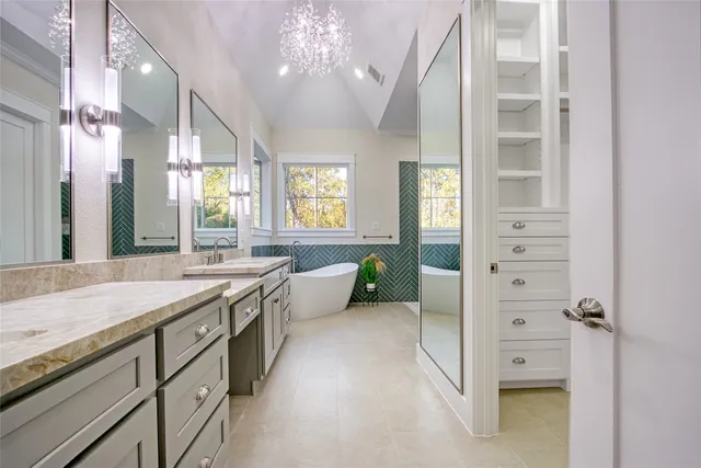 a spacious bathroom with a granite countertop sink a large mirror and a bathtub