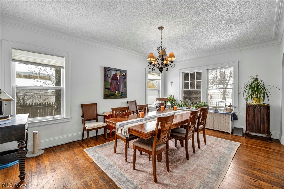 2410 Overlook Road Cleveland Heights, OH 44106 - Photo 12 of 50 Dining area featuring a textured ceiling, dark wood-style flooring, hanging lights, crown molding, and plenty of natural light