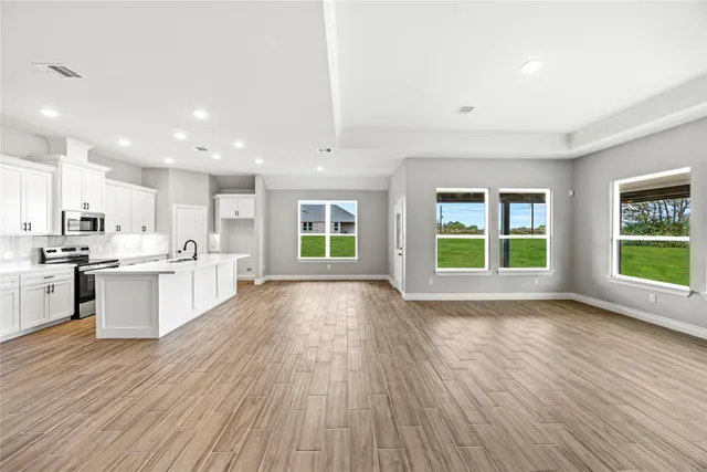 a large white kitchen with large windows and wooden floor
