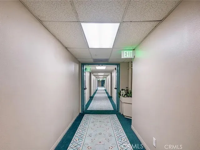 a view of a hallway to a livingroom with wooden floor and a large window