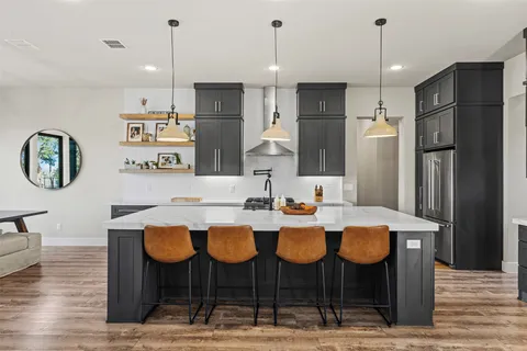 a kitchen with stainless steel appliances kitchen island granite countertop a dining table chairs and sink