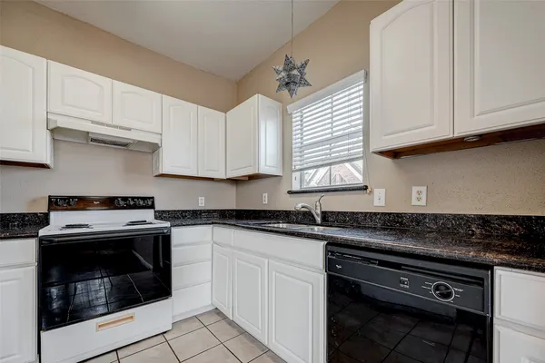 a kitchen with granite countertop white cabinets and window