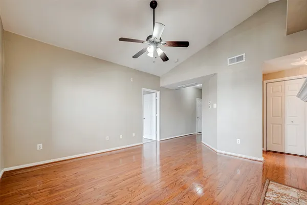 a view of an empty room with wooden floor and a fireplace