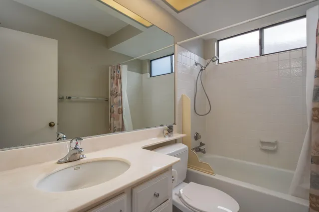 a bathroom with a granite countertop bathtub shower sink vanity and toilet