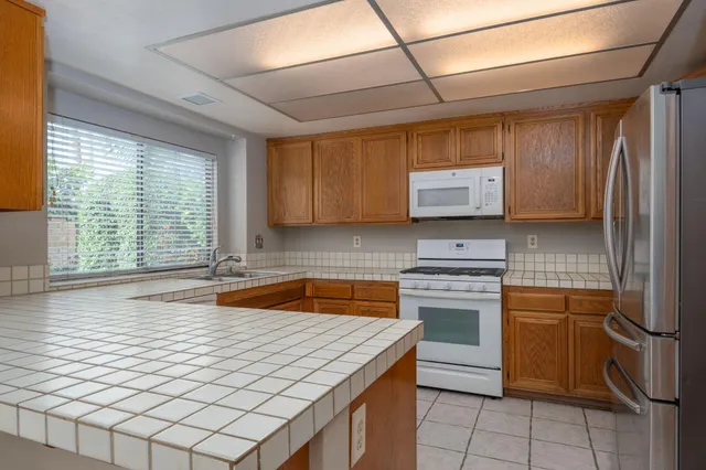 a kitchen with stainless steel appliances granite countertop a sink a stove a refrigerator a washer dryer and white cabinets