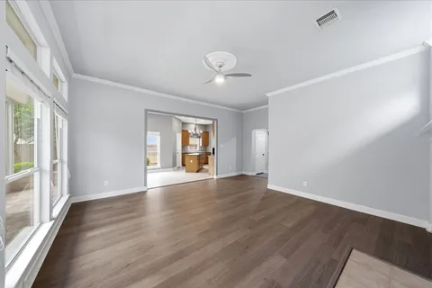 a view of an empty room with wooden floor and a window