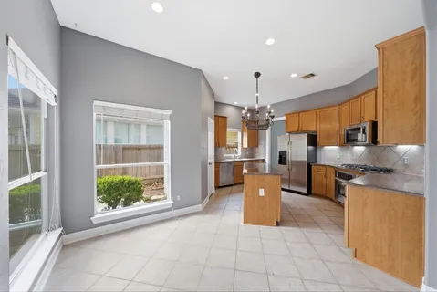 a large kitchen with stainless steel appliances kitchen island granite countertop a large counter top a refrigerator a stove a sink and a window