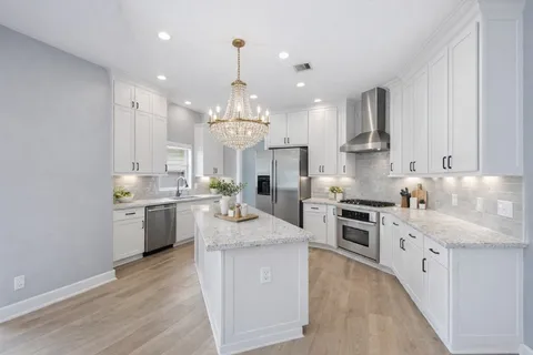 a large kitchen with kitchen island white cabinets and stainless steel appliances