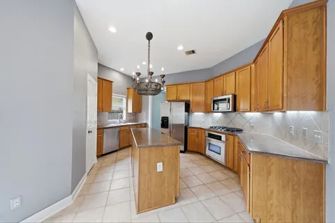 a large kitchen with stainless steel appliances granite countertop a sink dishwasher stove top oven and cabinets