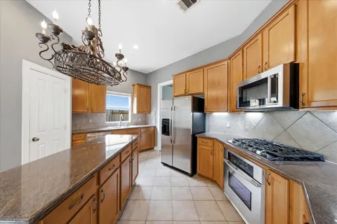 a kitchen with stainless steel appliances granite countertop a stove a sink and a refrigerator