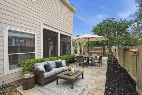 a view of a patio with couches table and chairs under an umbrella with a barbeque