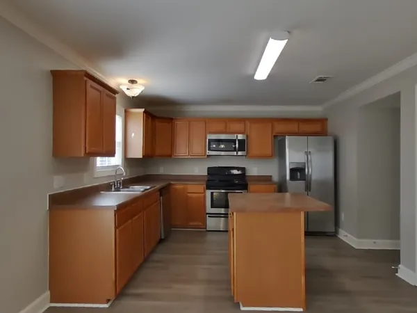 a kitchen with stainless steel appliances granite countertop a stove top oven a sink dishwasher a dining table and chairs with wooden floor