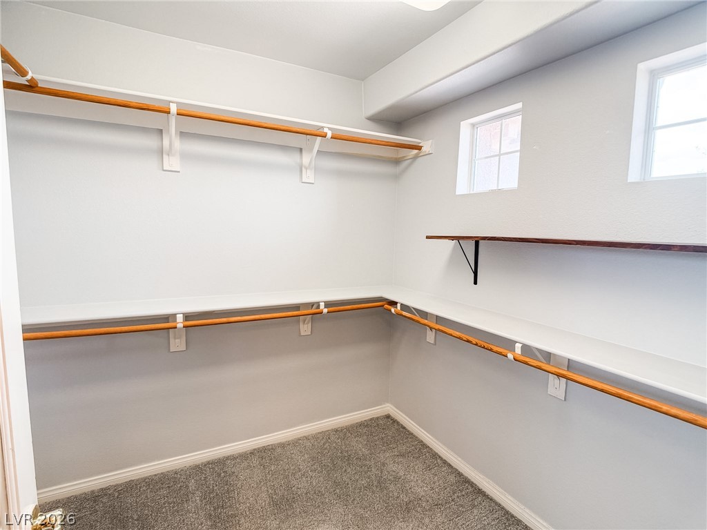 8683 Moreno Mountain Avenue Las Vegas, NV 89178 - Photo 19 of 26 A well-organized walk-in closet offers ample storage space, featuring shelving and hanging rods with natural illumination from two windows.