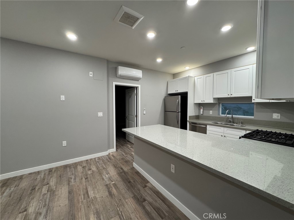 623 Normandie Avenue Los Angeles, CA 90004 - Photo 13 of 23 a large kitchen with stainless steel appliances a large counter top a stove and a refrigerator with wooden floor