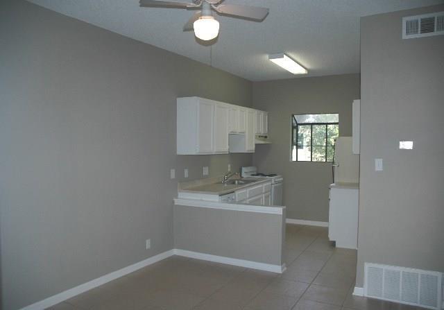 3206 King Street, Unit 202 Austin, TX 78705 - Photo 3 of 9 Kitchen featuring light countertops, white cabinets, white appliances, light tile patterned floors, and a ceiling fan