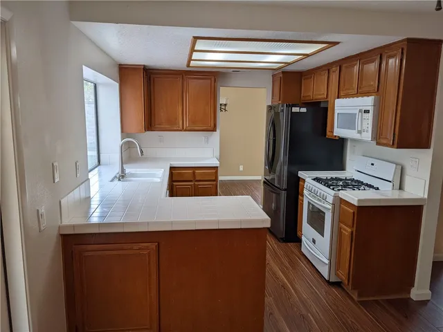 a kitchen with stainless steel appliances a refrigerator a sink and wooden cabinets