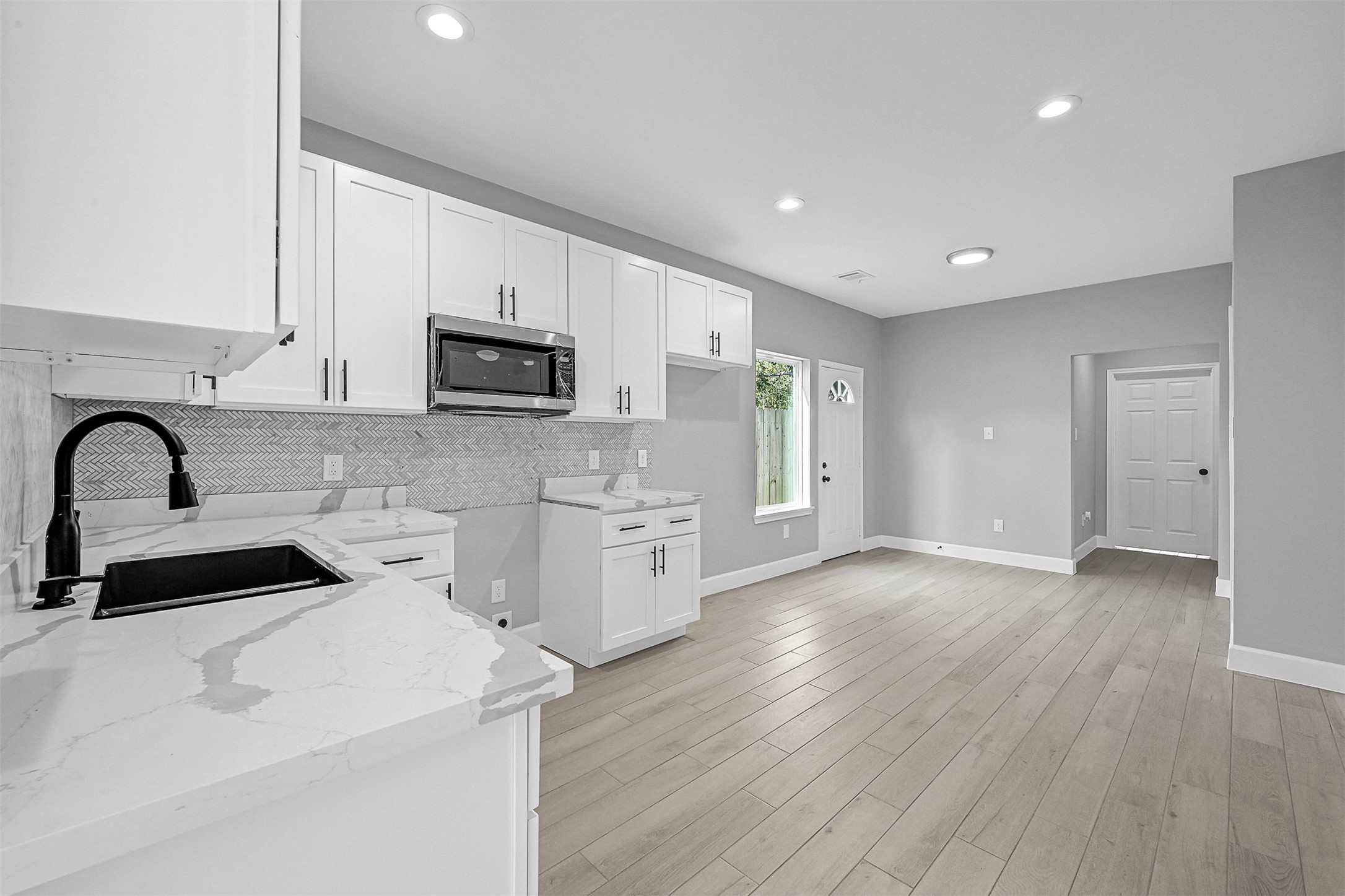 12009 Meadowgreen Street, Unit A Houston, TX 77076 - Photo 7 of 20 a kitchen with stainless steel appliances a stove top oven a sink and white cabinets with wooden floor