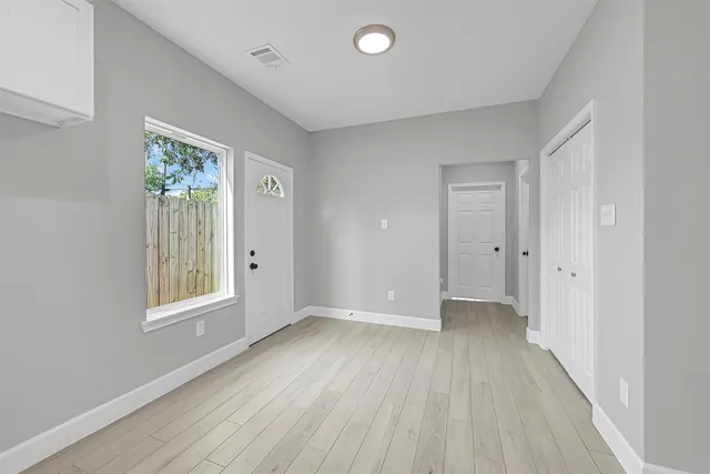 a view of an empty room with wooden floor and a window