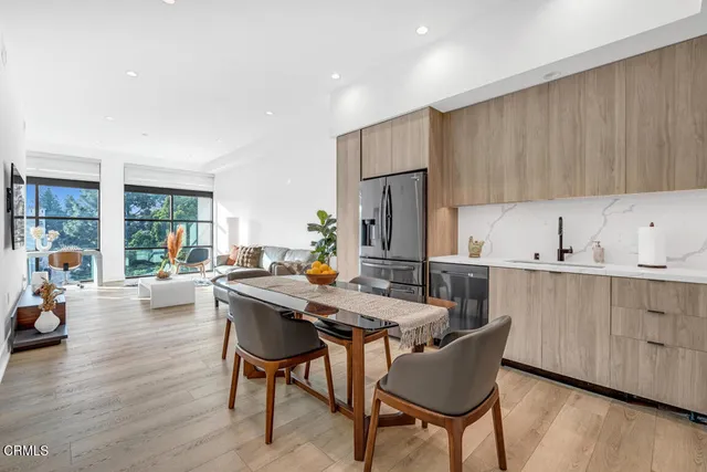 a kitchen with stainless steel appliances a dining table chairs and a refrigerator