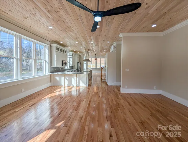 a view of a big room with wooden floor a ceiling fan and windows