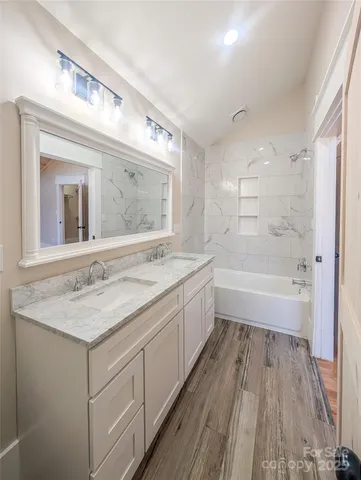 a bathroom with a granite countertop sink a mirror and a bathtub