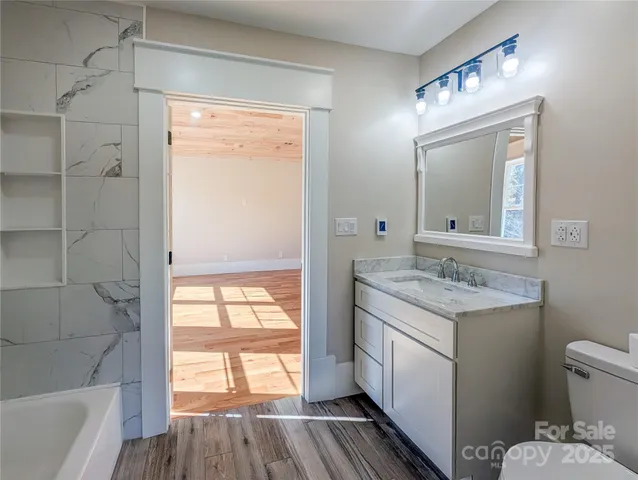 a bathroom with a granite countertop toilet a sink and a large mirror