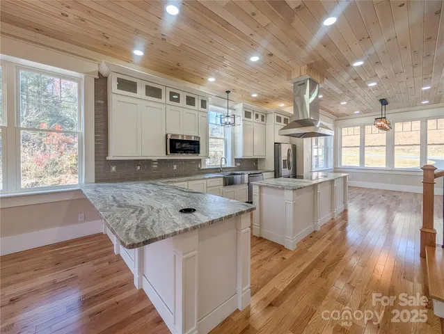 a kitchen with stainless steel appliances granite countertop a lot of counter space and wooden floors