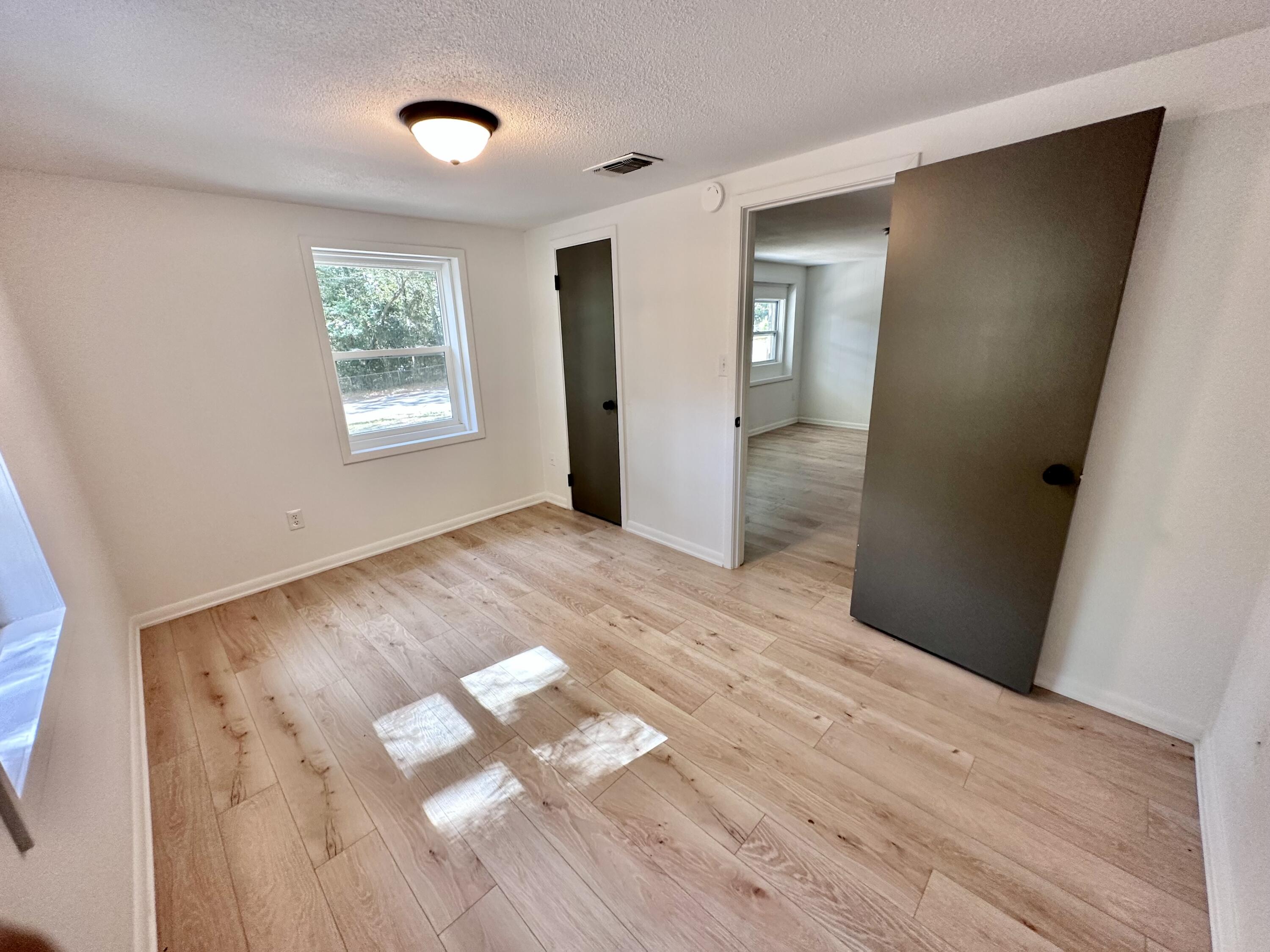 159 Smith Street Crestview, FL 32539 - Photo 17 of 29 a view of an empty room with wooden floor and a window
